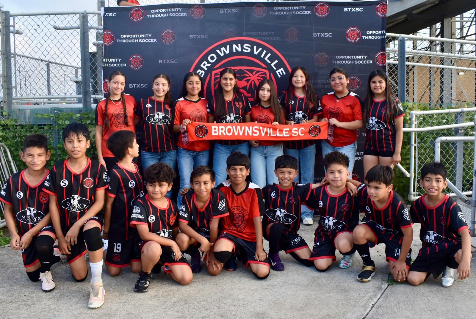 Young BTX players and fans in Suspiros Cakes shirts at a Semi-Pro game